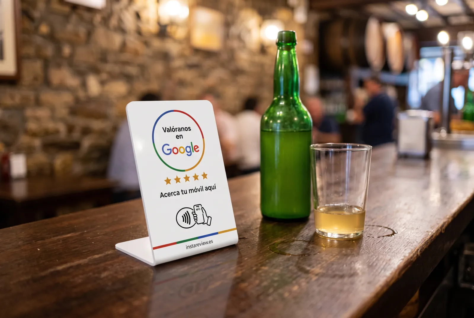 Expositor NFC de Instareview en la barra de una sidrería asturiana, junto a una botella y un vaso de sidra